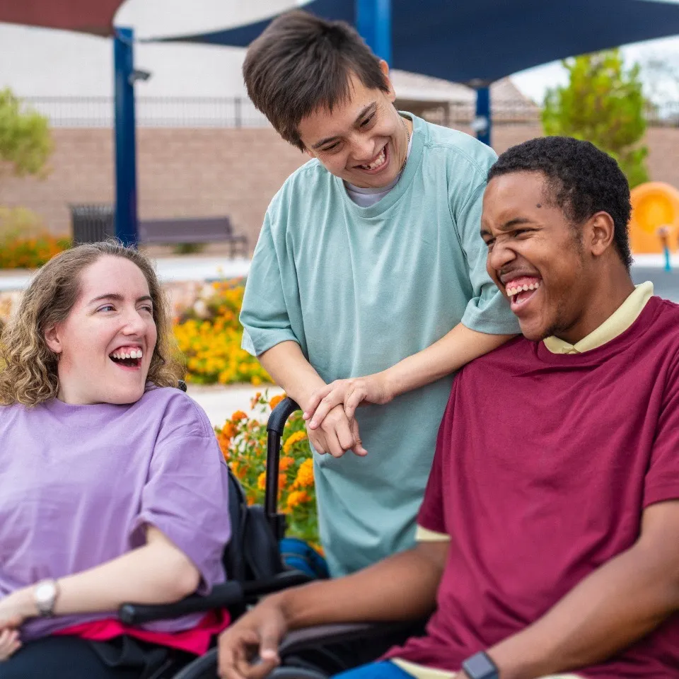 Three young people with disability laughing together outdoors